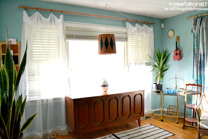 sheer sequin and fringe accented curtains flank credenza